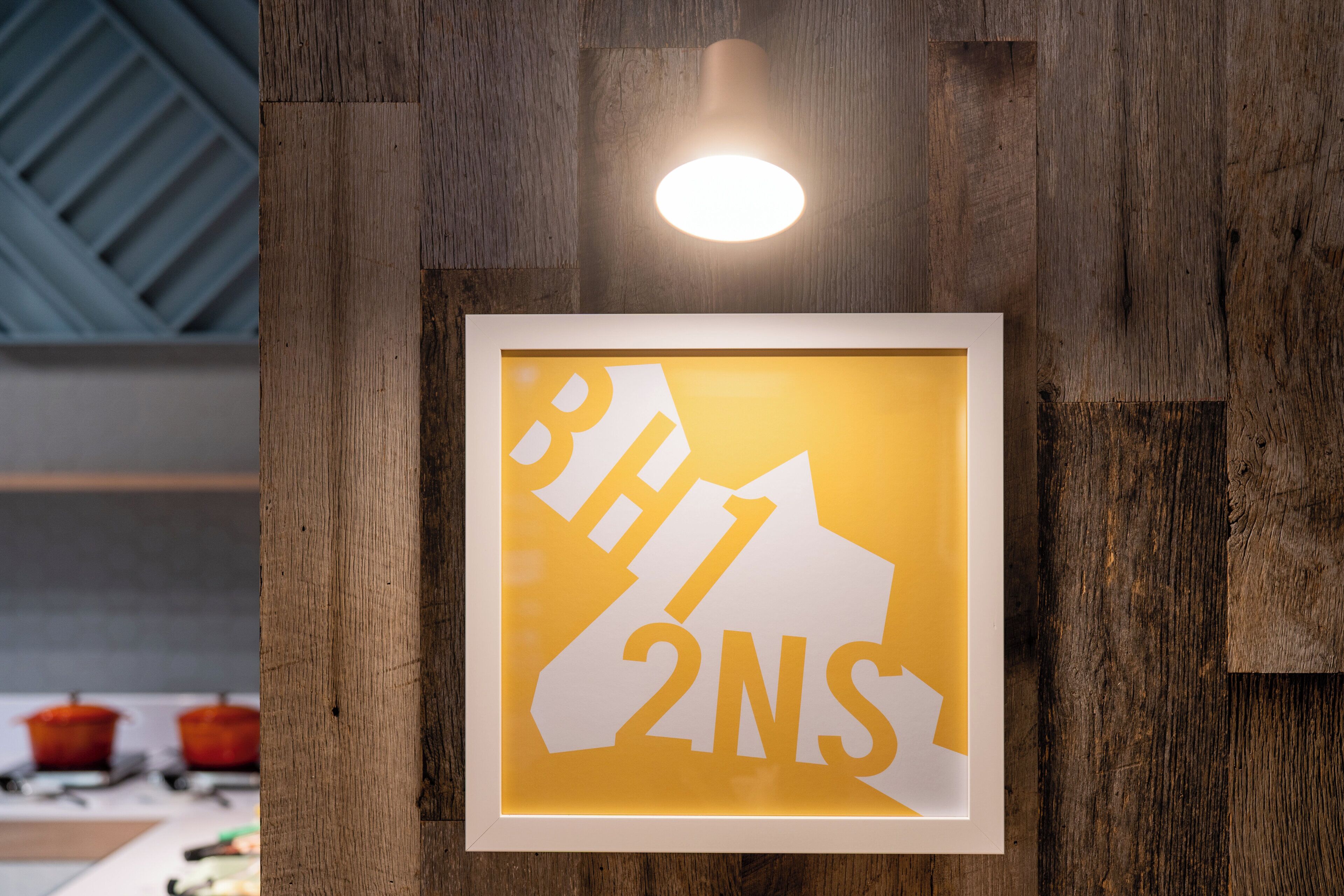A framed sign with the text 'BH1 2NS' on a wooden wall.