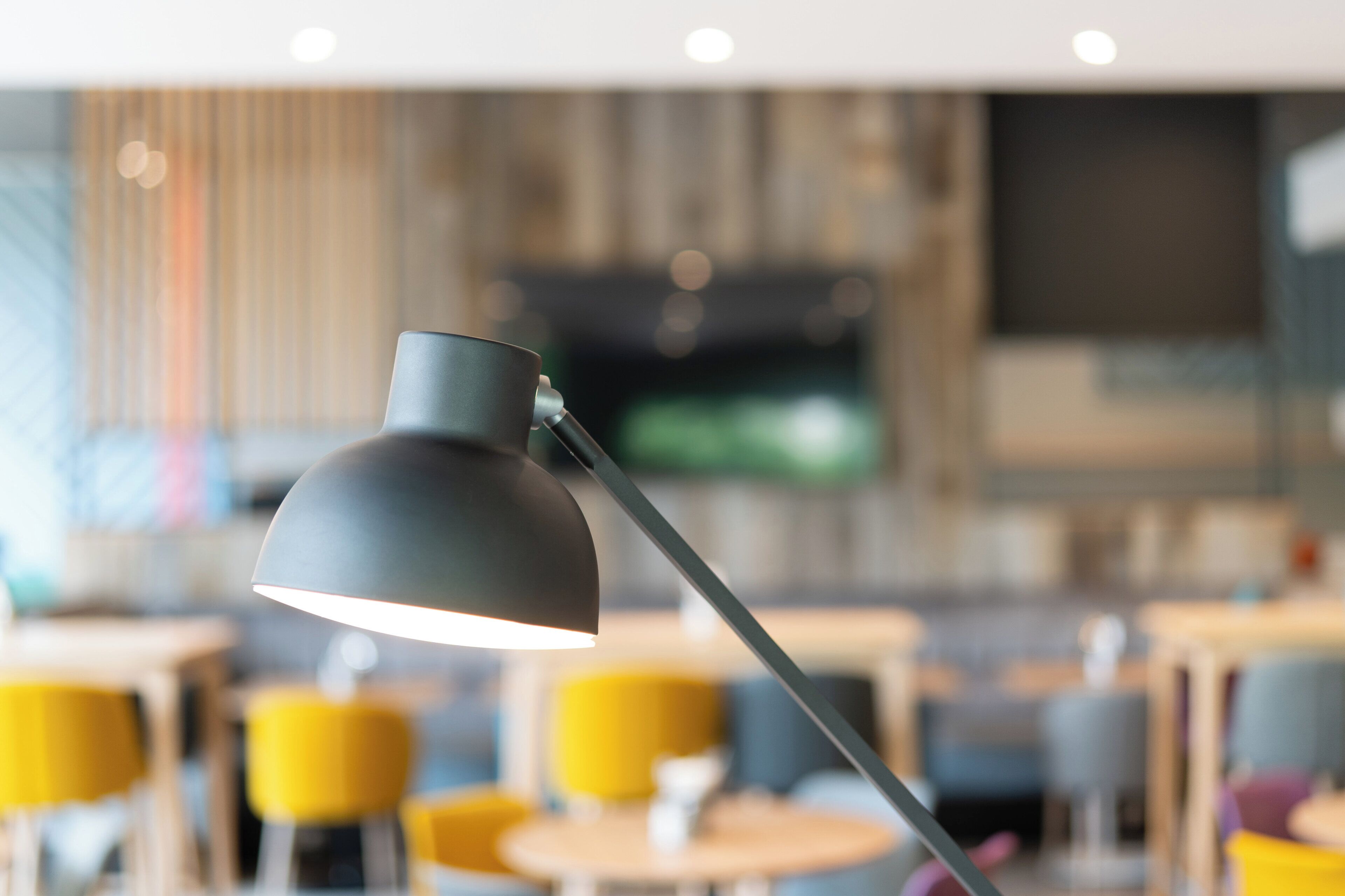 Um interior moderno com uma luminária de mesa, cadeiras amarelas e uma televisão ao fundo.