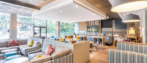 A modern interior with a central seating area, a kitchen, and large windows.