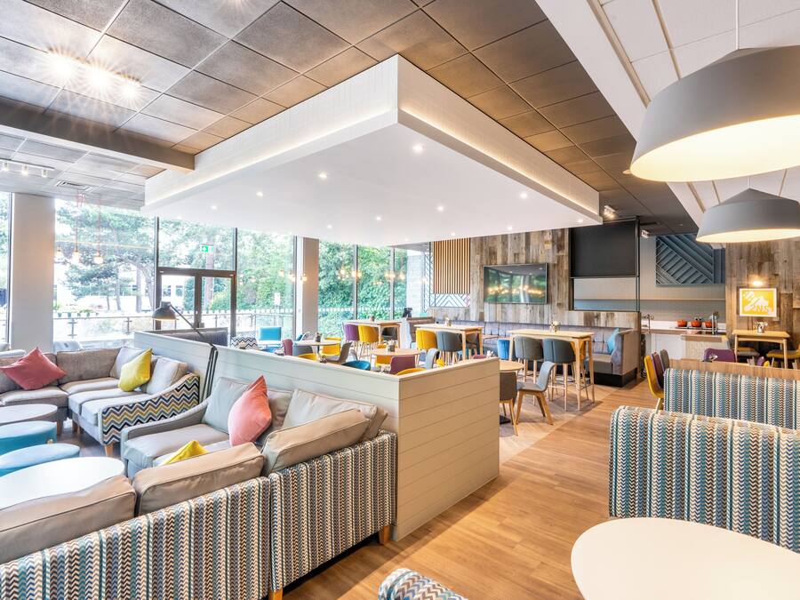 A modern interior with a central seating area, a kitchen, and large windows.