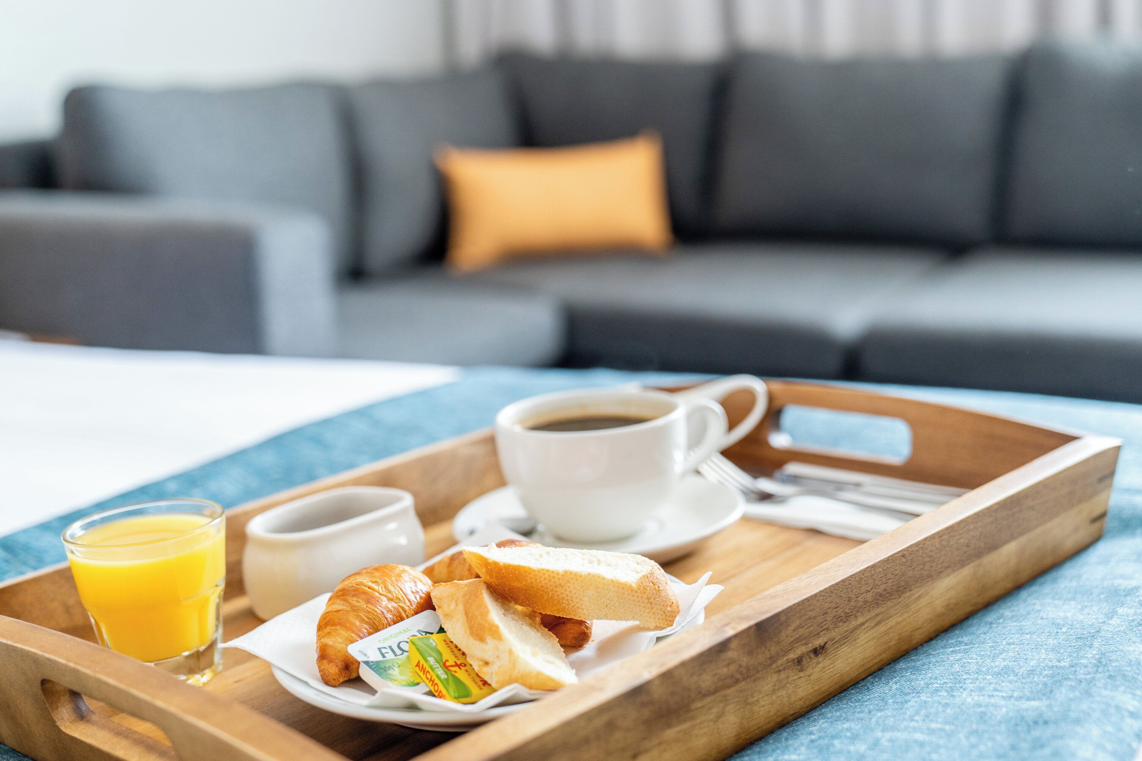 A breakfast tray with croissants, juice, and coffee on a wooden tray.