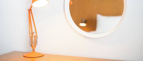 A round mirror on a wall with a wooden table in front.