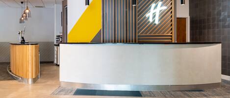 A reception desk with a modern design, featuring a geometric pattern and a prominent 't' logo.