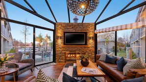 A modern living room with a stone fireplace, leather sofas, and a large TV. - Club Wyndham Wanaka, Trademark Collection by Wyndham (Wanaka)