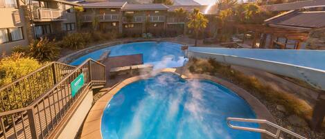 Alberca al aire libre, sombrillas en la alberca y camastros