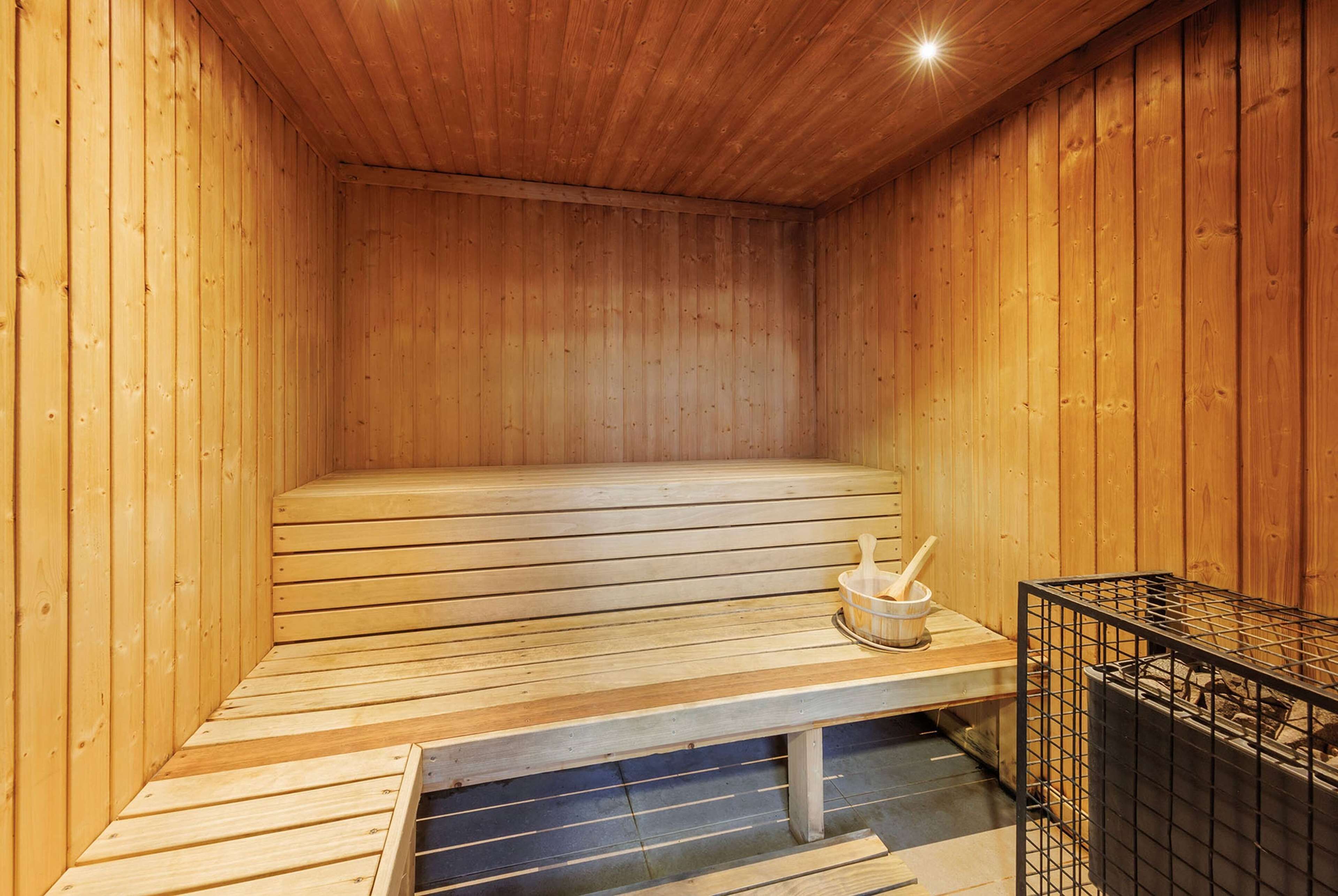 A sauna with wooden benches and a bench with a bucket and brush.