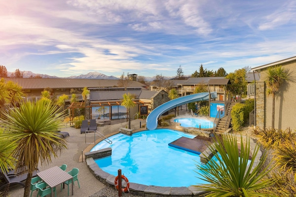 Una piscina al aire libre, sombrillas, sillones reclinables de piscina