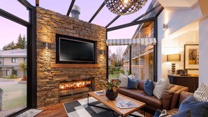 A modern living room with a stone fireplace, leather sofa, and a large TV. - Club Wyndham Wanaka, Trademark Collection by Wyndham (Wanaka)