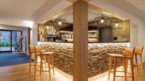 A modern bar area with a stone wall, wooden bar stools, and hanging pendant lights. - Club Wyndham Wanaka, Trademark Collection by Wyndham (Wanaka)