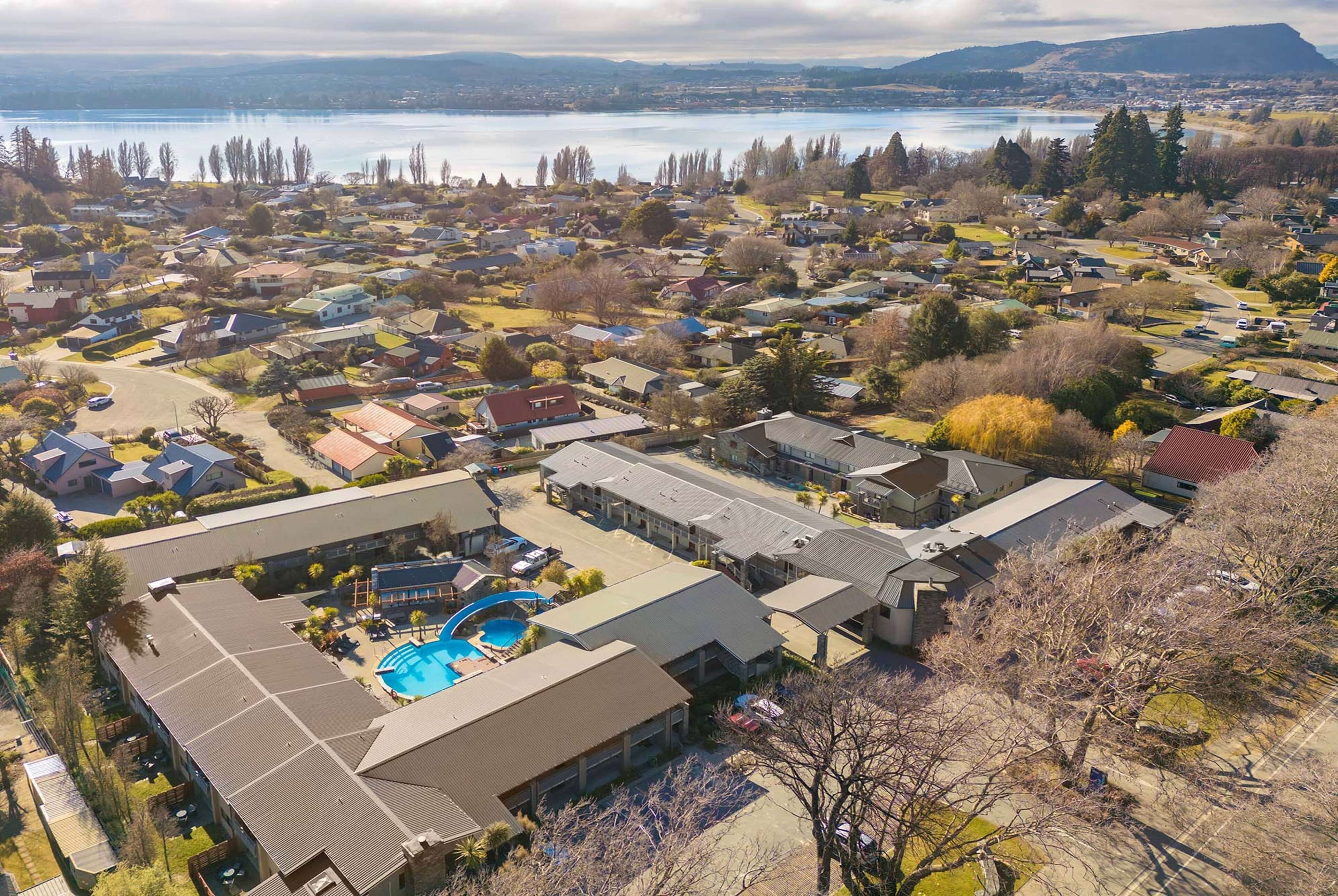 An aerial view of a residential area with houses, a swimming pool, and a large building with a flat roof.
