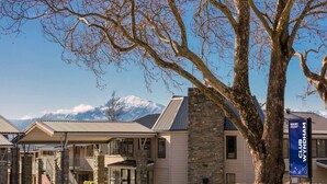 A resort building with a stone facade, a covered entrance, and a mountain view in the background. - Club Wyndham Wanaka, Trademark Collection by Wyndham (Wanaka)