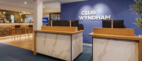 A reception area with marble counters and a blue wall displaying the name 'CLUB WYNDHAM'.