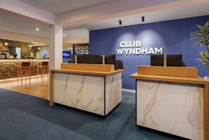 A reception area with marble counters and a blue wall displaying the name 'CLUB WYNDHAM'. - Club Wyndham Wanaka, Trademark Collection by Wyndham (Wanaka)
