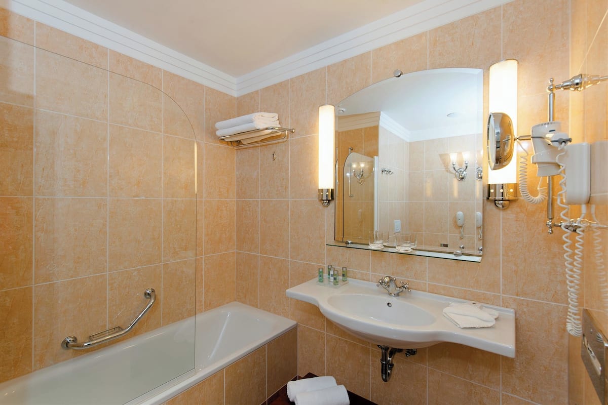 A bathroom with a bathtub, a sink, a mirror, and a towel rack.