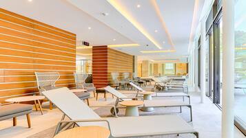 Ein moderner Lounge-Bereich mit Sitzgelegenheiten und Tischen, großen Fenstern und einer Wand als Holzdekor.