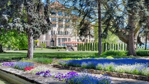 A large building with a garden in front, featuring a variety of flowers and trees. - Ensana Thermia Palace (Piestany)