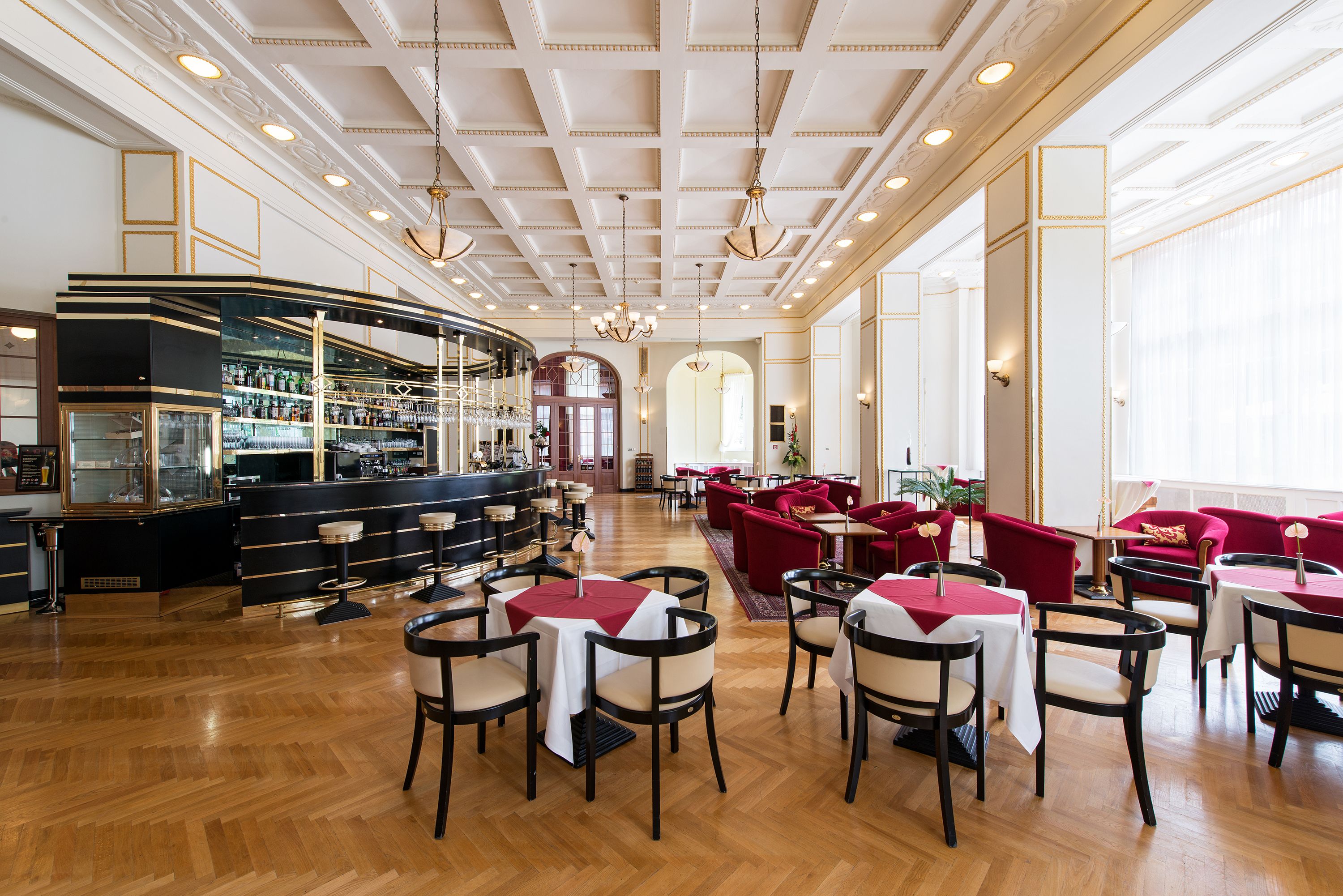 Ein geräumiges Restaurant mit Bar, Holzboden und roten Sitzmöbeln.