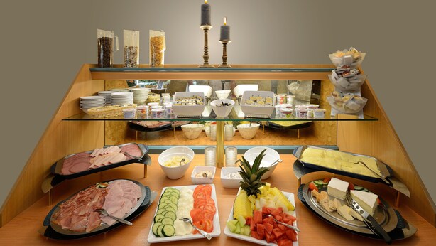 A buffet with various food items, including meats, cheeses, and fruits. - Hotel Nordic (Norderstedt)