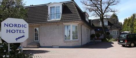 A Nordic Hotel with a traditional architectural style, featuring a prominent entrance and a vehicle parked in front.