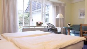 A hotel room with a bed, a desk, a chair, and a window with curtains. - Hotel Nordic (Norderstedt)