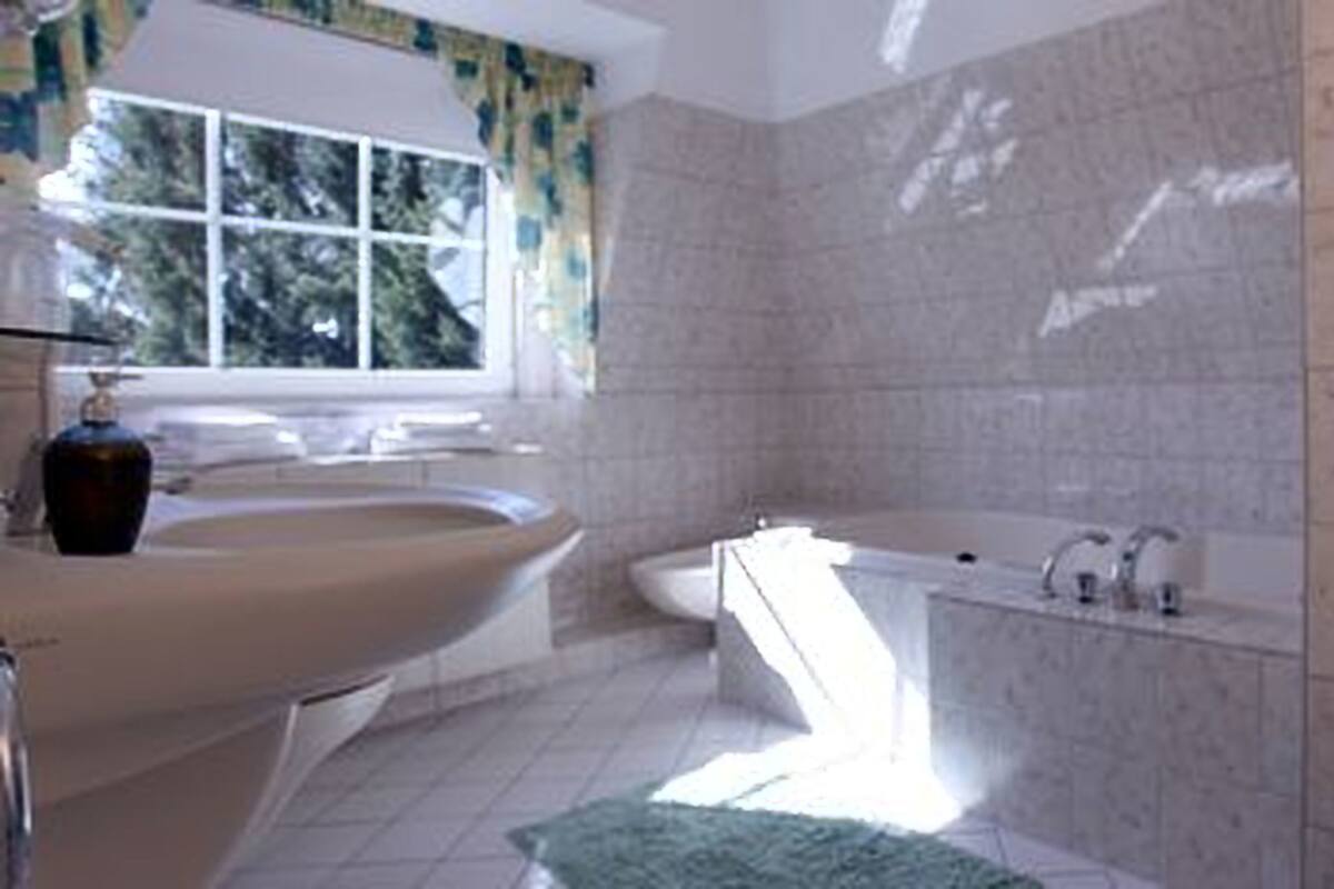 A bathroom with a bathtub, a sink, and a window with curtains.
