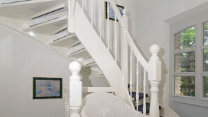 A white staircase with blue carpeted steps and a white chair with a blue cushion. - Hotel Nordic (Norderstedt)