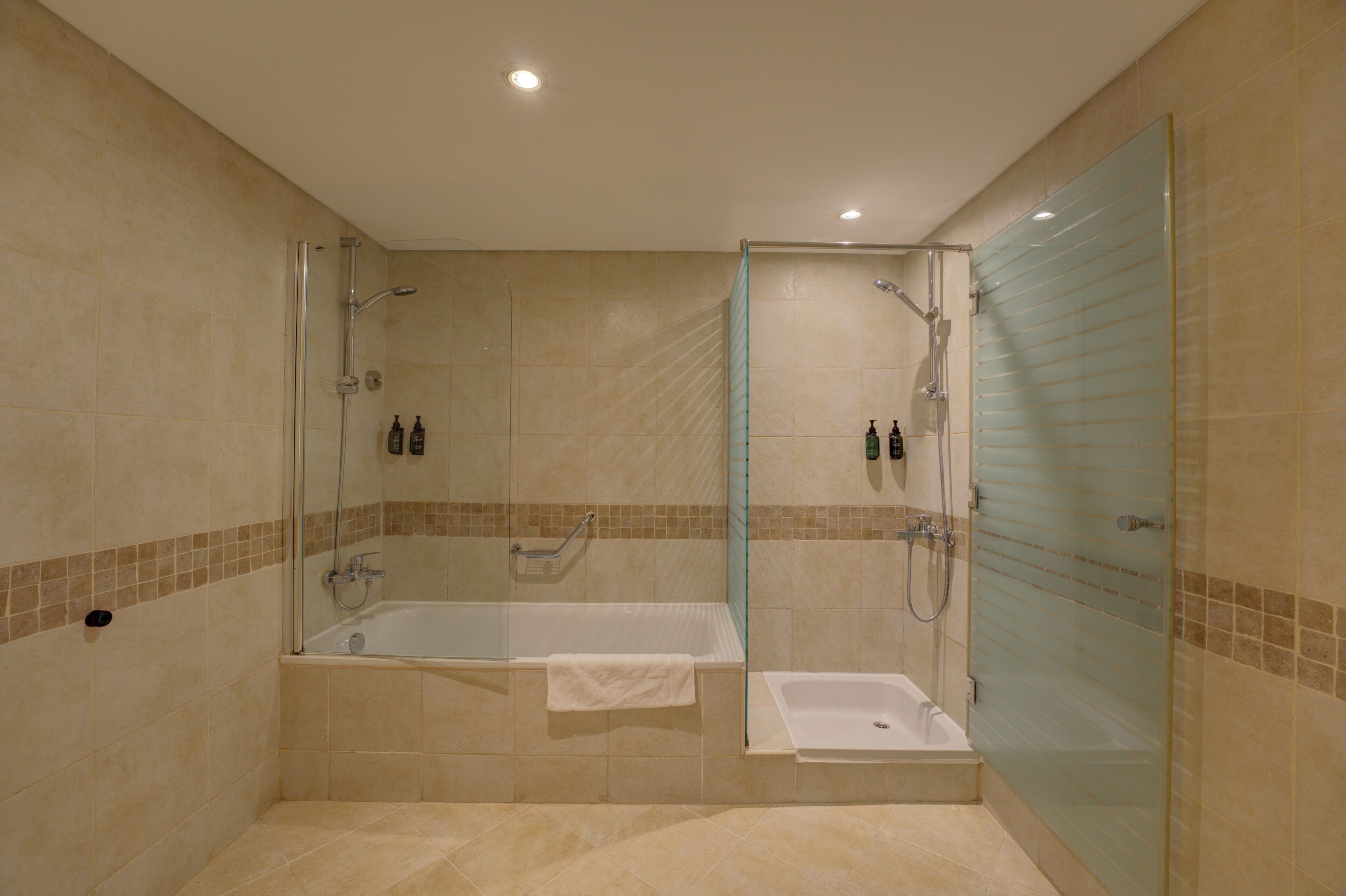 Een moderne badkamer met een douchecabine van glas, een vrijstaand bad en een glazen douchedeur.