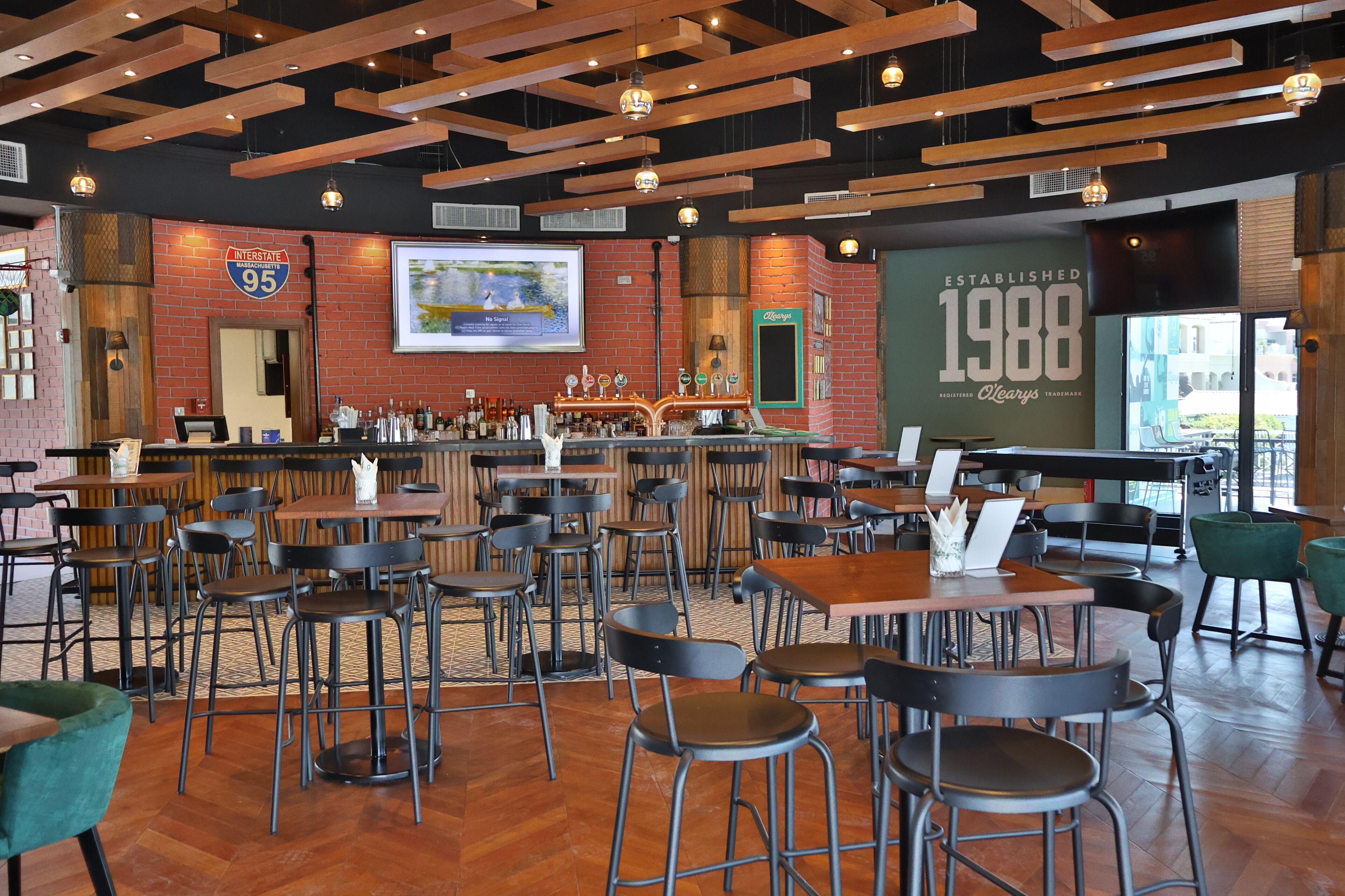 A spacious bar area with multiple seating options, a prominent display of the year 1988, and a large screen showing a scenic view.