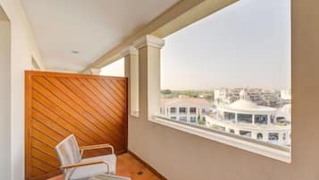 A balcony with a view of a cityscape, a chair, and a tiled floor.