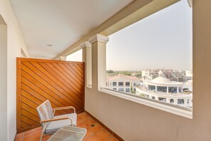 A balcony with a wooden partition, a white chair, and a view of buildings in the distance. - Millennium Lakeview Hotel (Dubai)