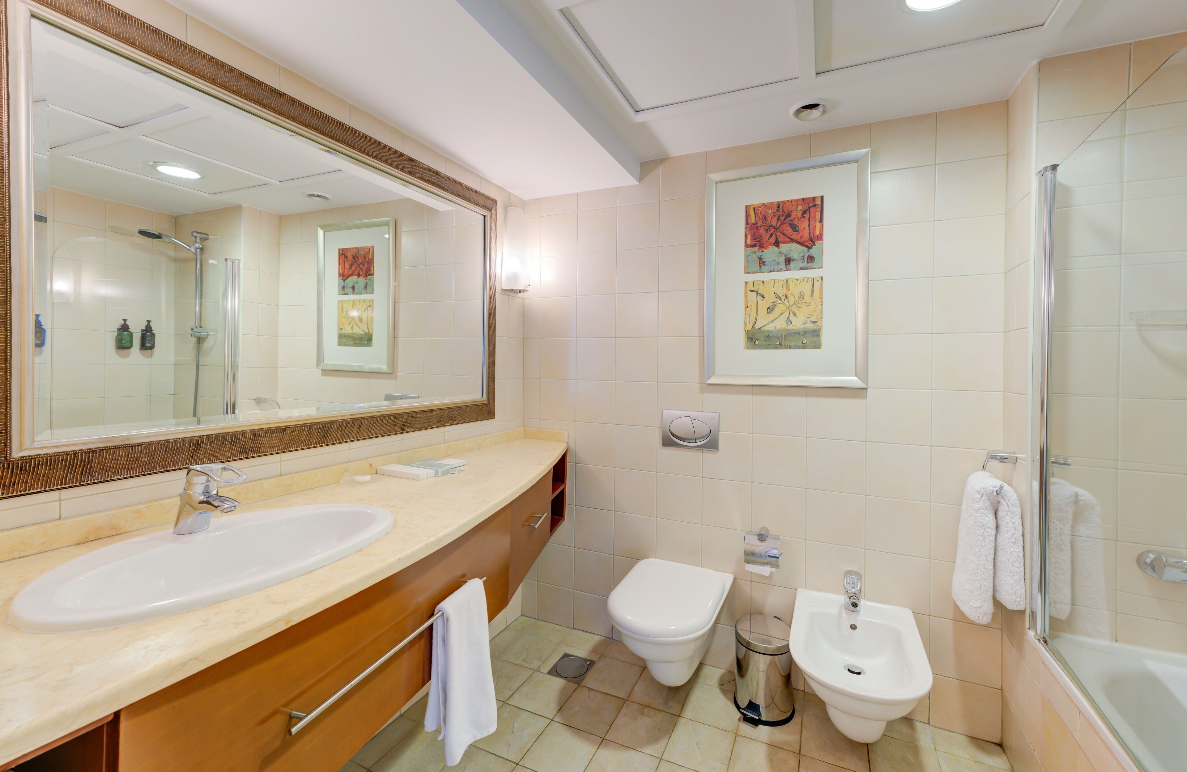 A modern bathroom with a large sink, toilet, bidet, and shower.