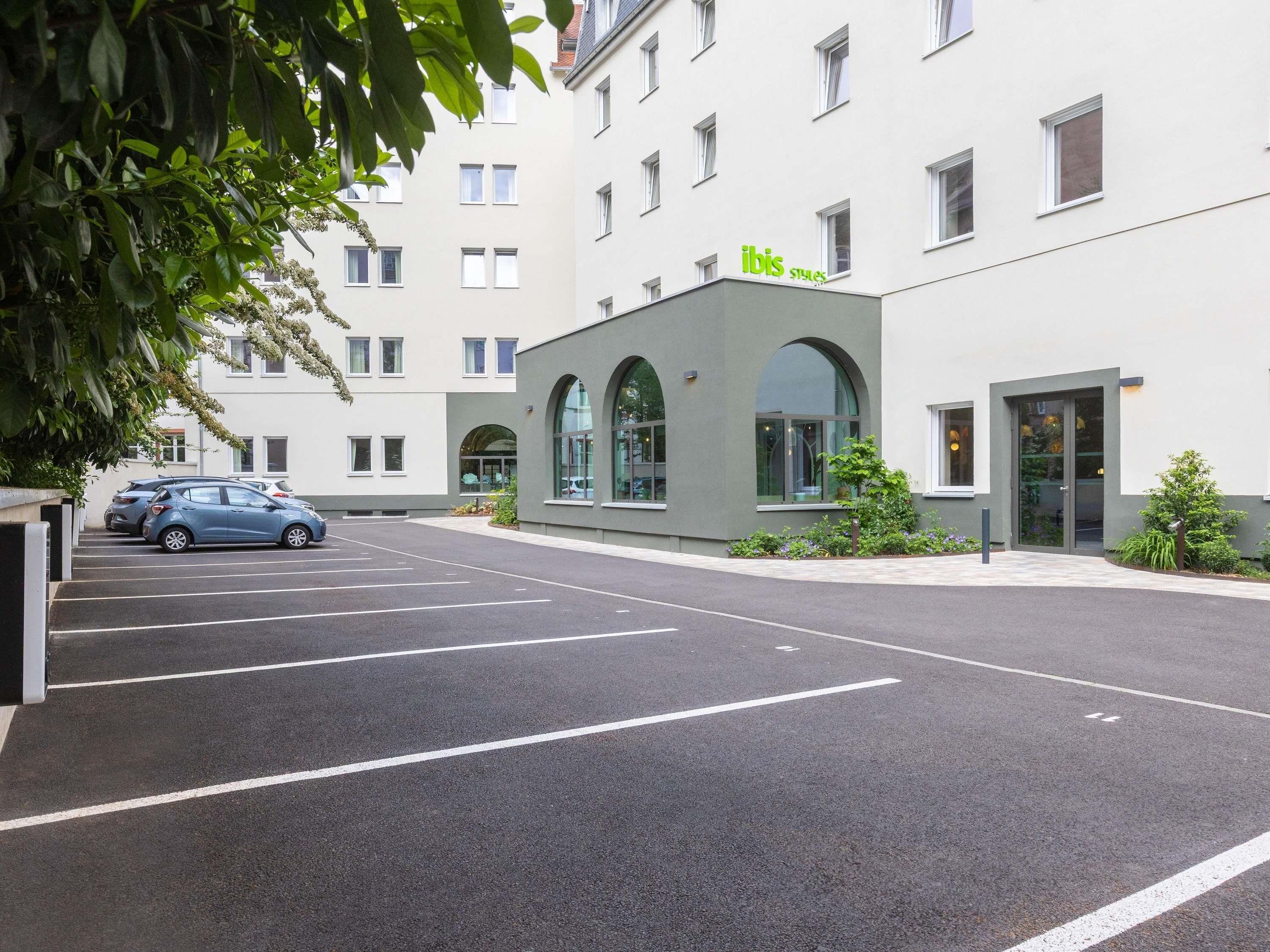 A modern building with a parking lot and a car parked in front.