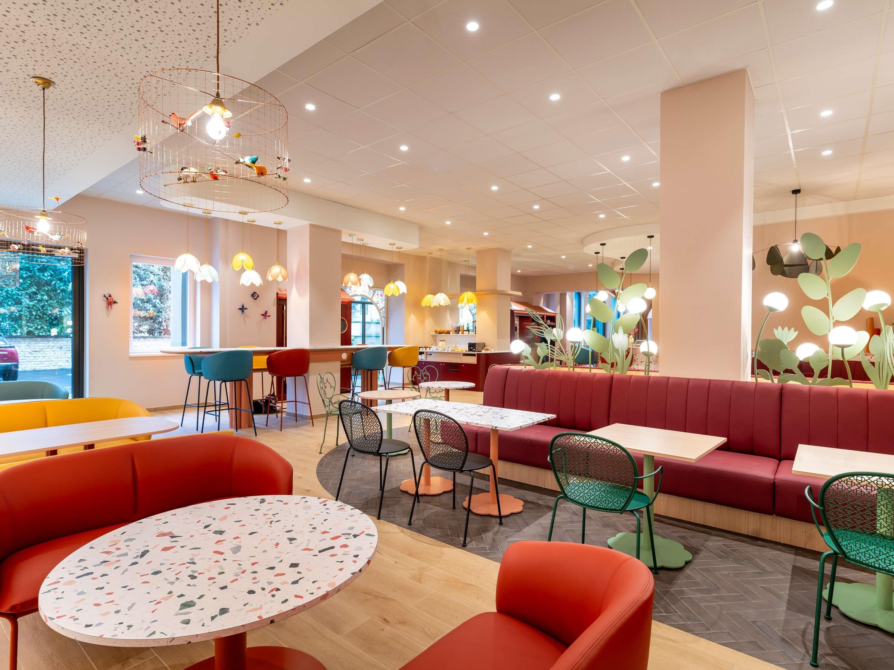 Un interior de restaurante moderno con mesas redondas, sillas coloridas e iluminación de techo original.