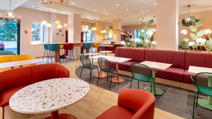 A modern restaurant interior with round tables, colorful chairs, and unique ceiling lights. - ibis Styles Strasbourg Centre République (Strasbourg)