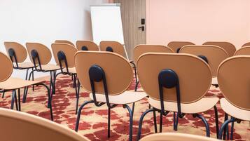 Une salle de conférence avec des rangées de chaises, un tableau blanc et une porte.