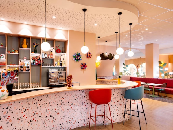 A modern bar area with a terrazzo floor, a coffee machine, and shelves stocked with bottles and glasses.