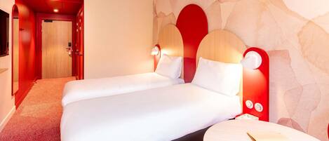 A hotel room with a double bed, a round side table, and a stone-patterned wall.
