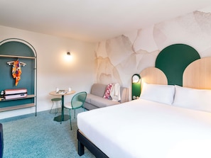 Une chambre d’hôtel comprenant un lit, un bureau, une chaise, une armoire et un mur au décor original.