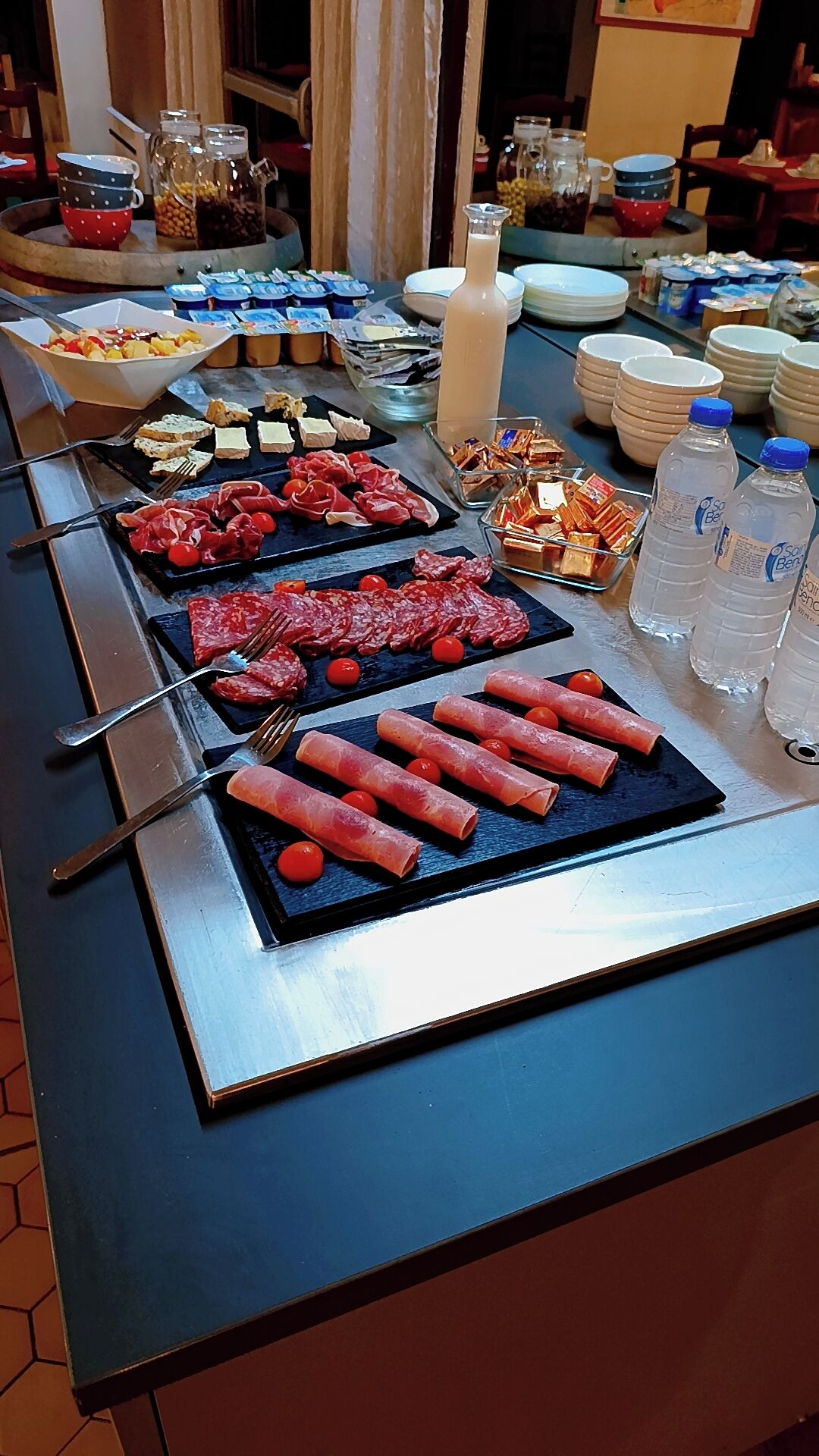 A buffet with various food items including meats, cheeses, and condiments.