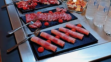 A buffet with various food items including meats, cheeses, and condiments.