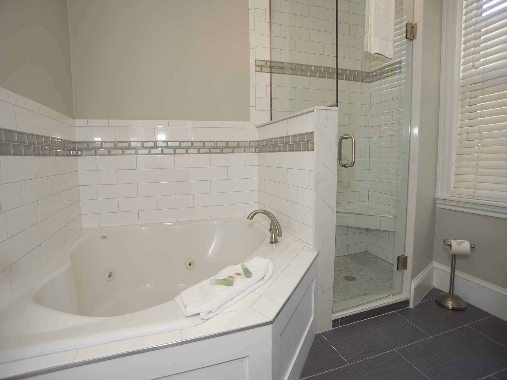 Un baño con bañera, cabina de ducha de vidrio y retrete.