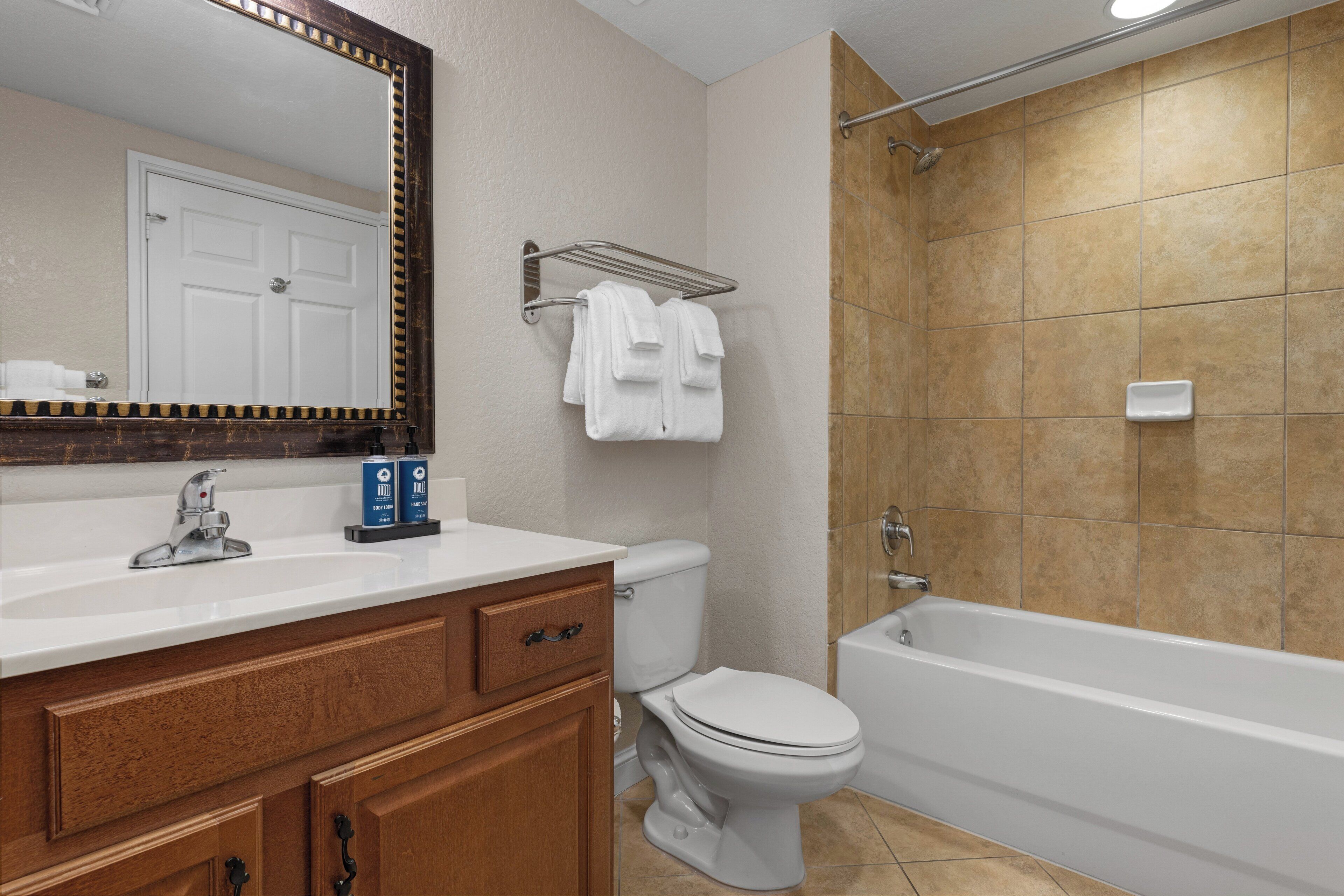 A bathroom with a white sink, a mirror, a toilet, and a bathtub.