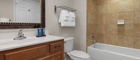 A bathroom with a white sink, a mirror, a toilet, and a bathtub.