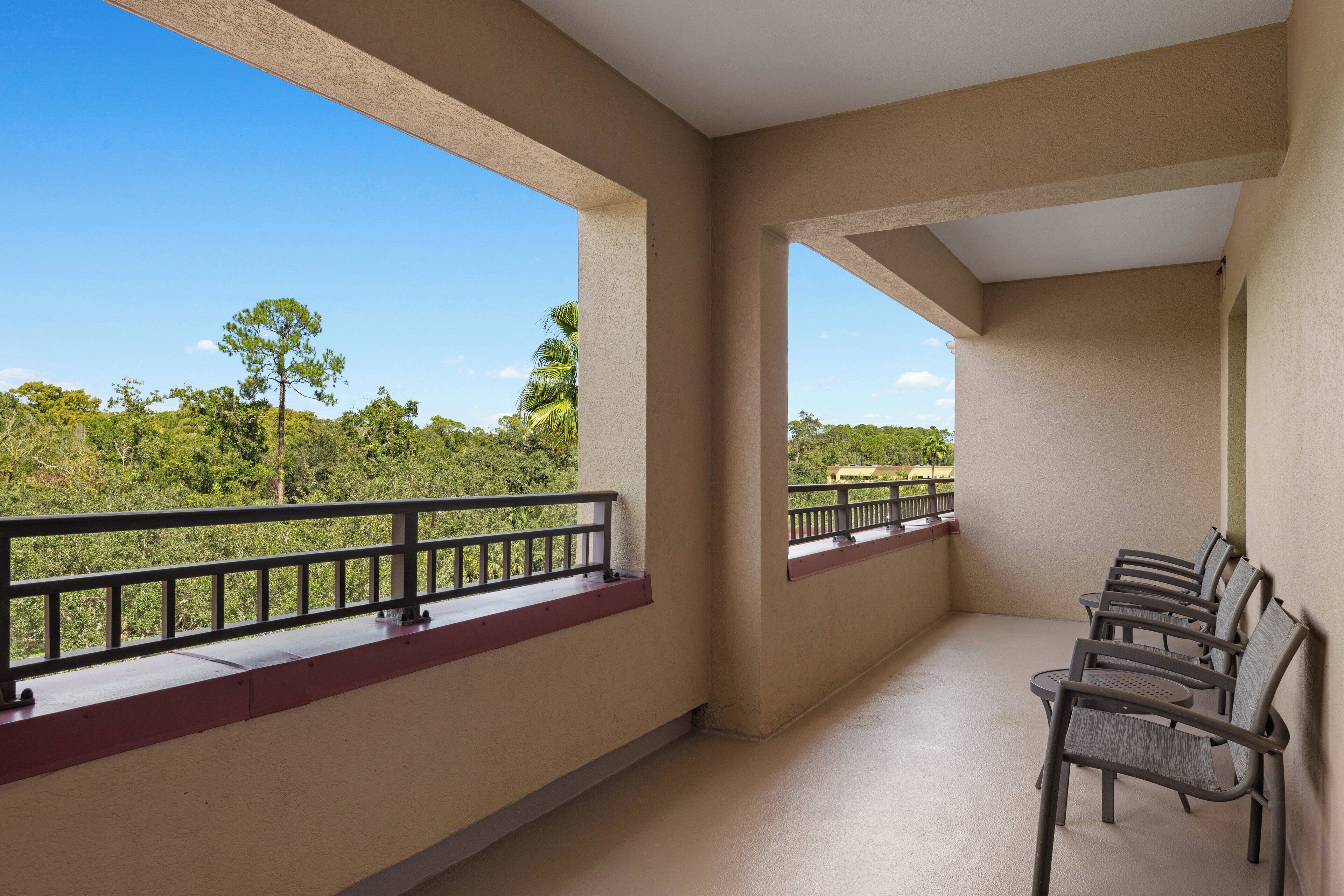Ein Balkon mit Blick auf Bäume und einen klaren Himmel.