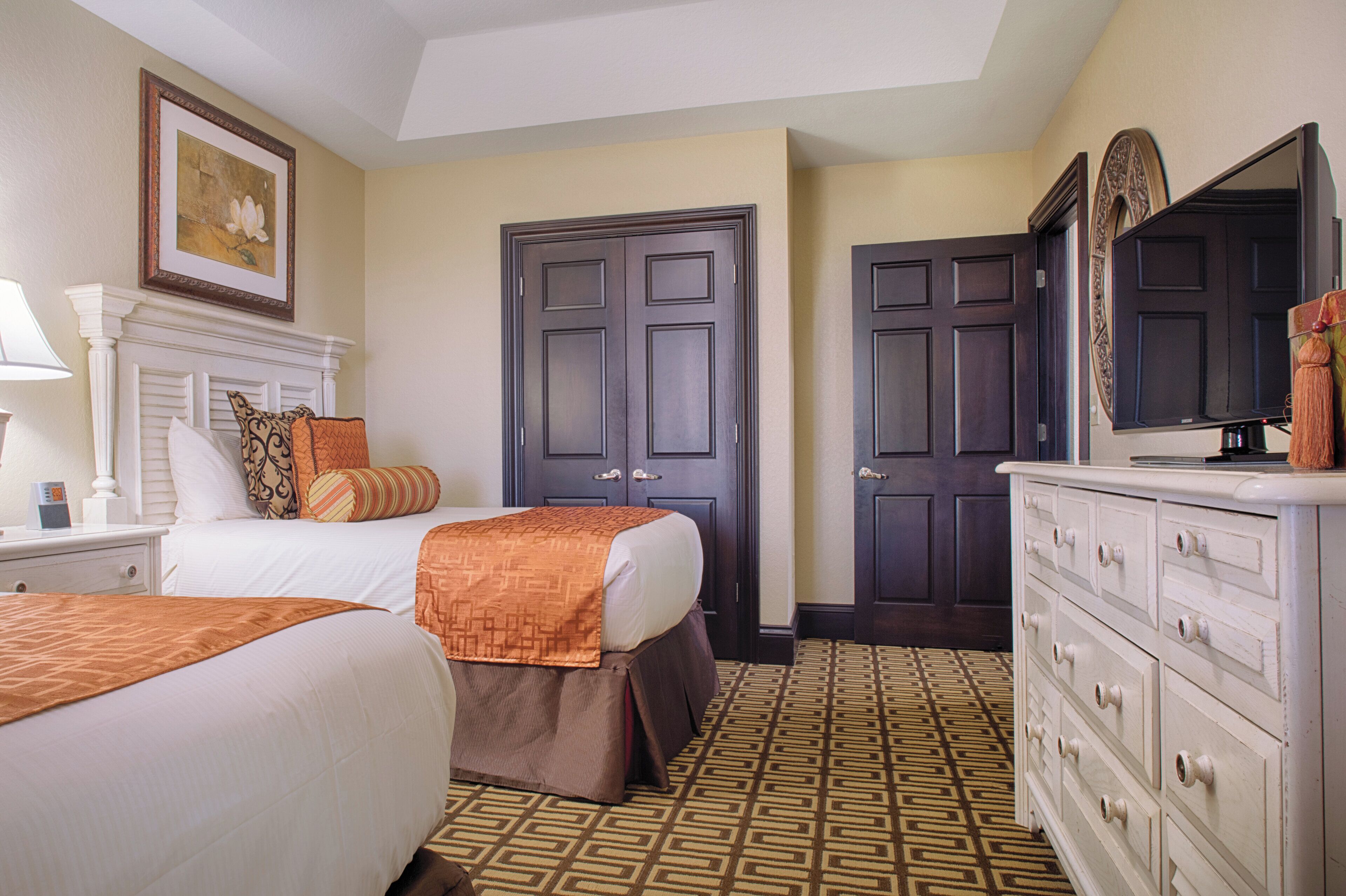 Une chambre d’hôtel avec deux lits, une commode, un miroir et un tableau encadré au mur.