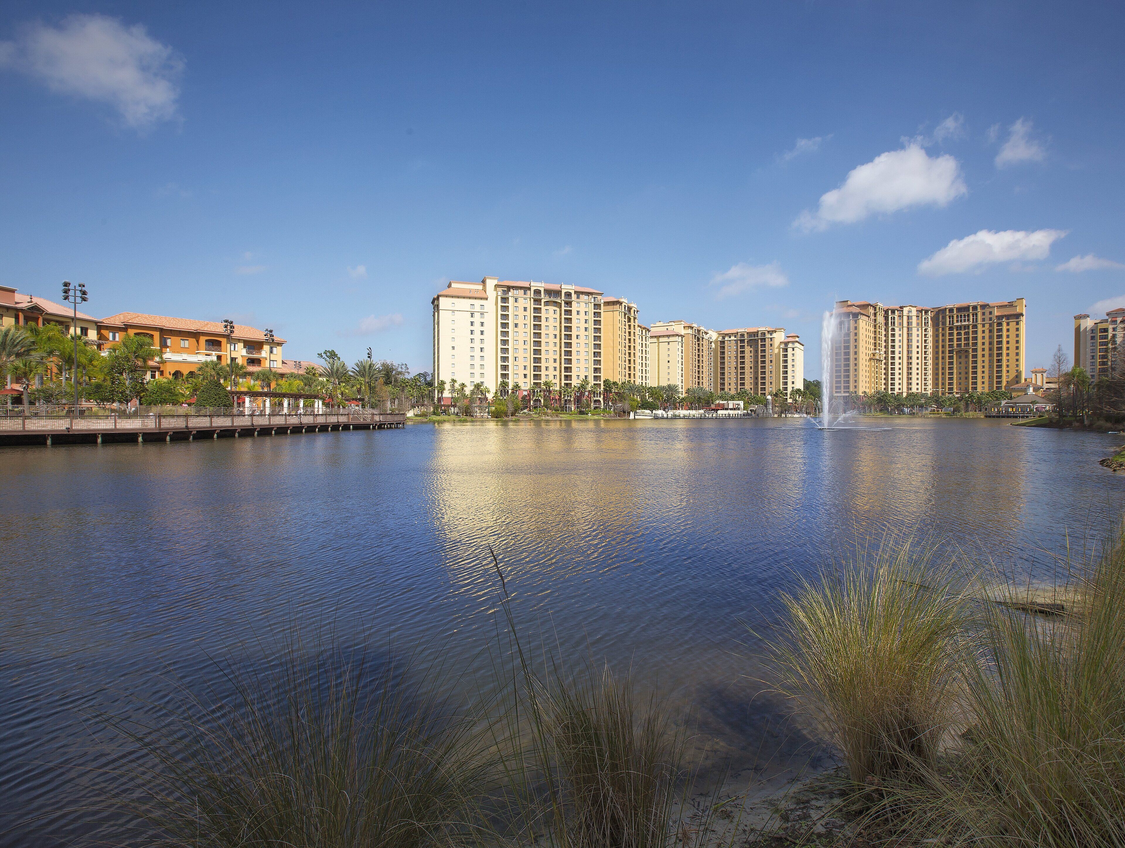 A large body of water with a fountain, surrounded by high-rise buildings and palm trees.
