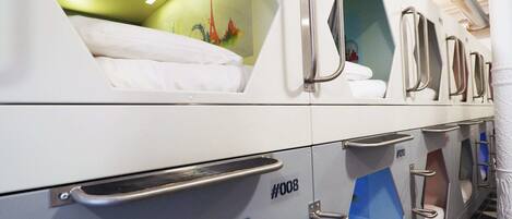 A row of bunk beds with metal handles, a green wall with a mural, and a patterned floor.