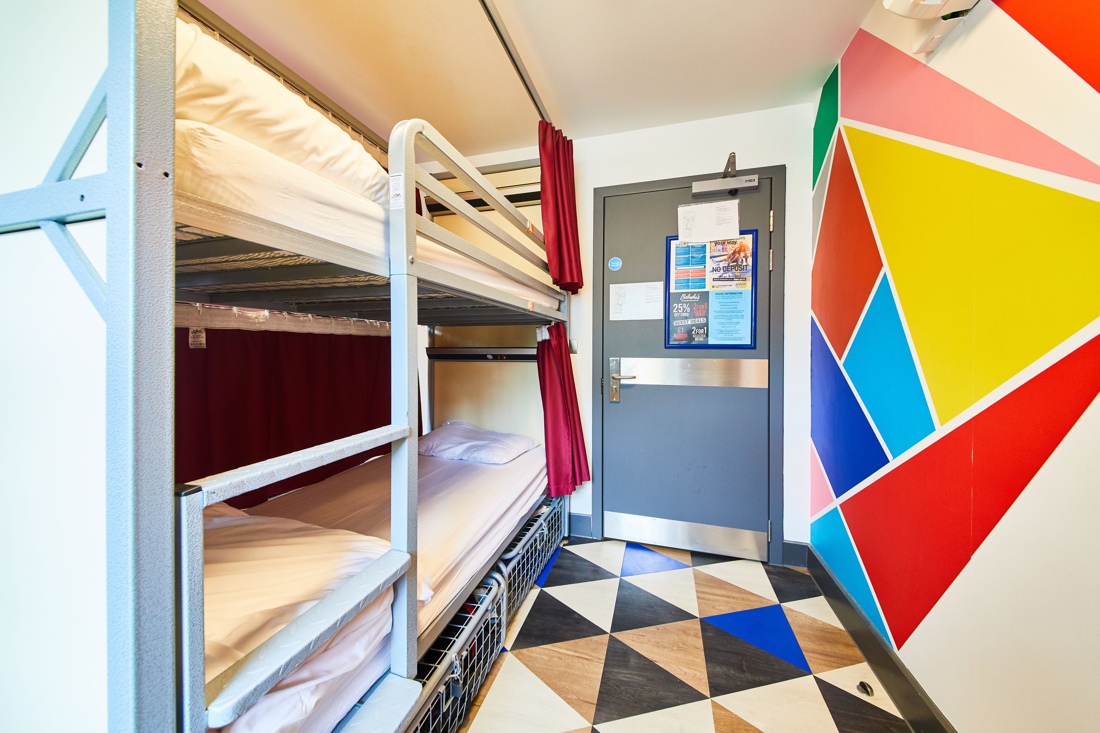 A bunk bed room with a door and a colorful geometric wall.