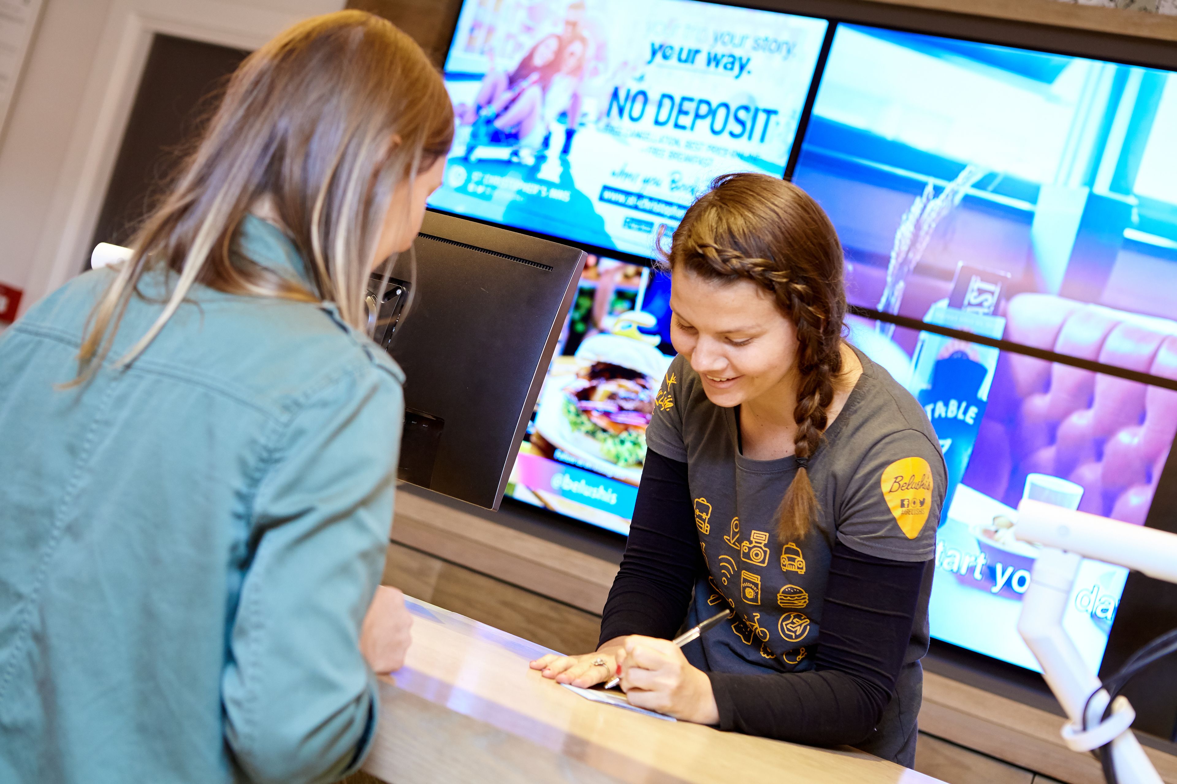 Twee personen bij een balie, met een digitaal menu zichtbaar op de achtergrond.