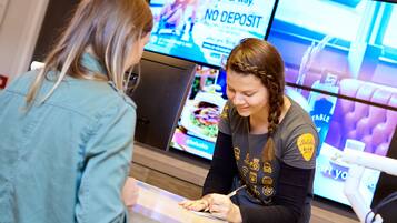 Twee personen bij een balie, met een digitaal menu zichtbaar op de achtergrond.